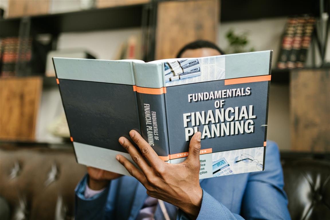 Person Reading a Book About Fundamentals of Financial Planning - Credit: Photo by RODNAE Productions from Pexels